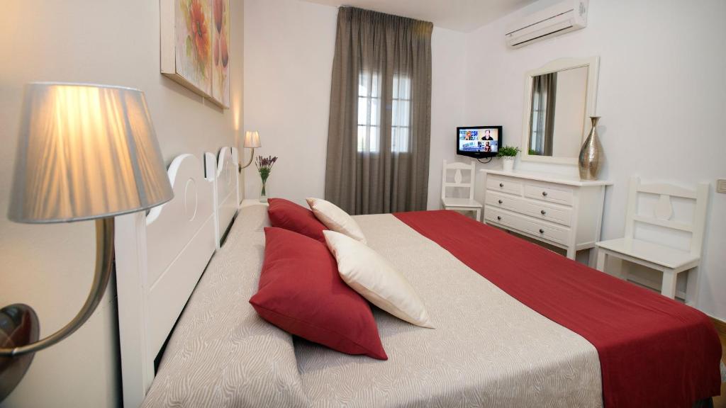 a bedroom with a large bed with red pillows at Leo San Bruno in Isla Canela