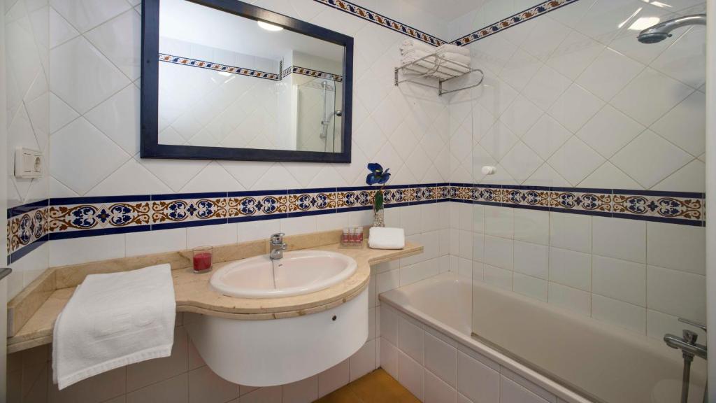 a bathroom with a sink and a tub and a mirror at Leo San Bruno in Isla Canela