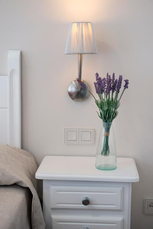 a table with a lamp and a vase with flowers on it at Leo San Bruno in Isla Canela