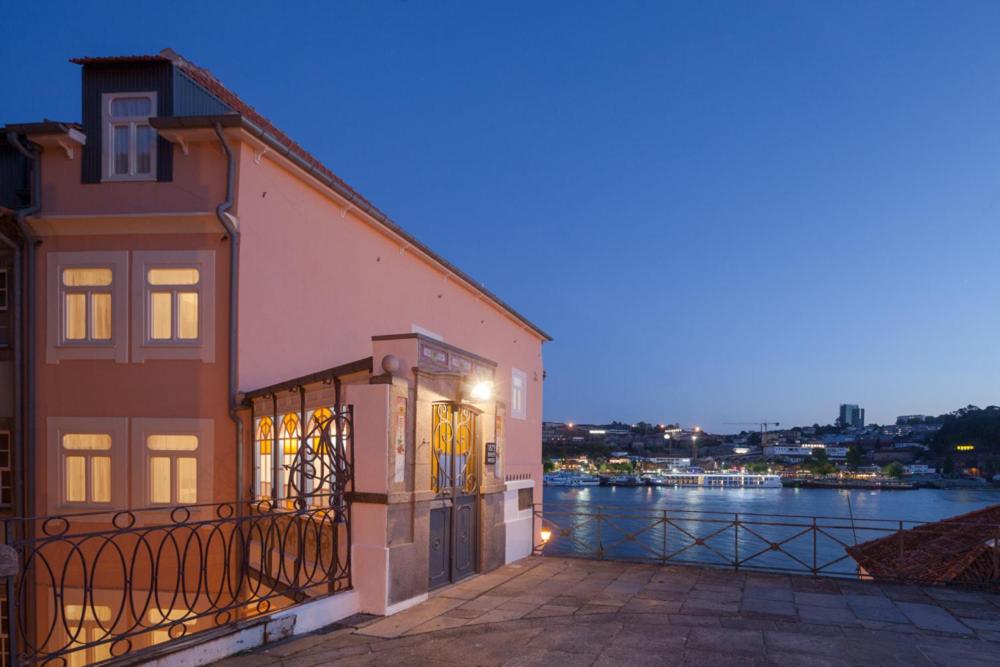 a building with a balcony next to a body of water at 1872 River House by Olivia in Porto