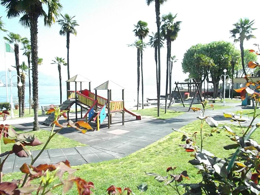 a park with swings and a playground with palm trees at Appartamento Angelina in Stresa