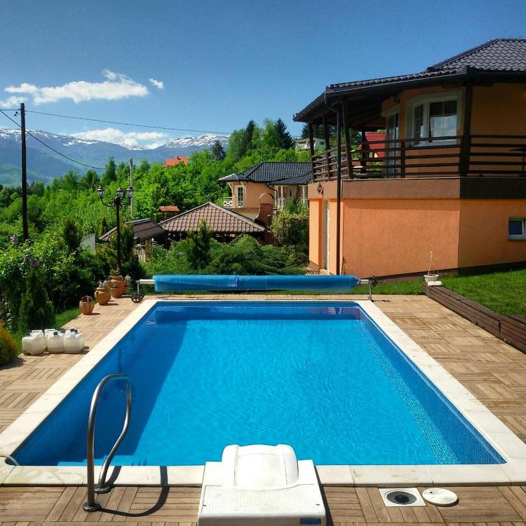a large blue swimming pool in front of a house at Vila Sani in Sarajevo