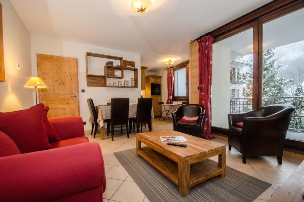 een woonkamer met een rode bank en stoelen en een tafel bij Résidence Le Paradis in Chamonix-Mont-Blanc