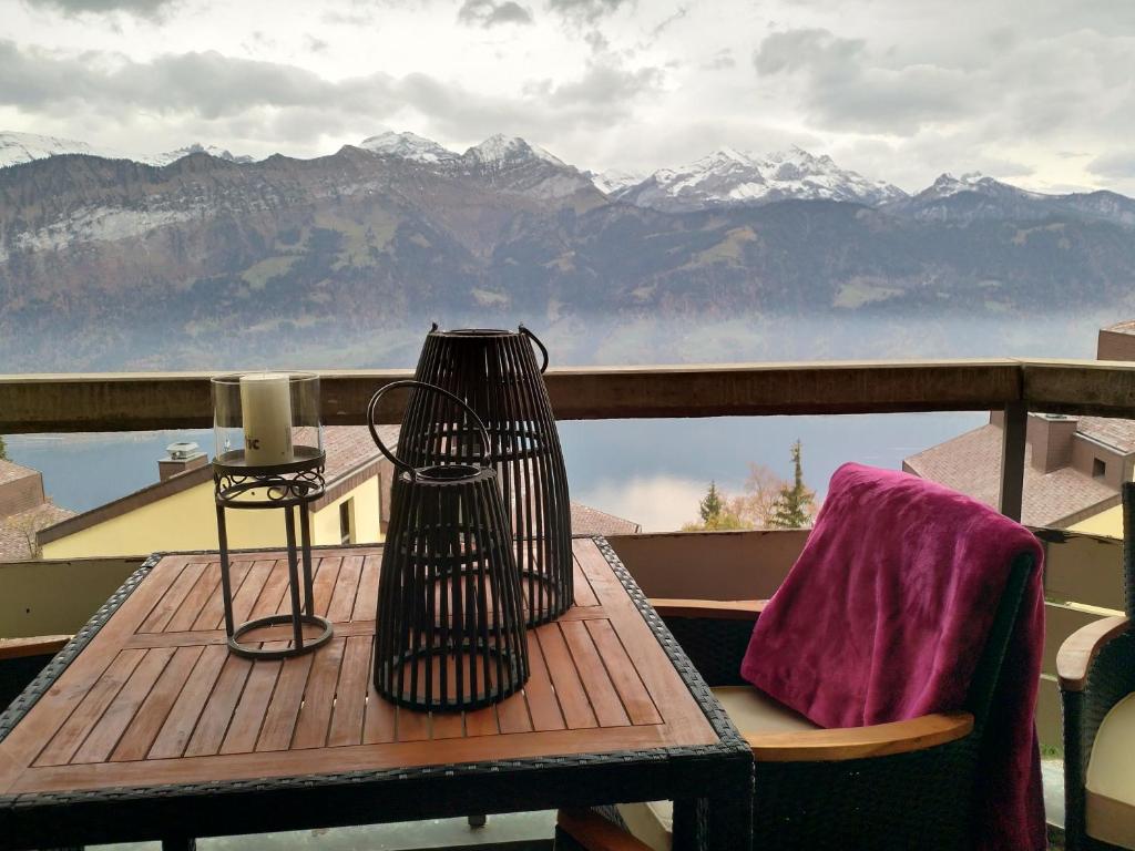 un tavolo con lampada su un balcone con vista sulle montagne di Swiss Seeblick Apartment mit Hotelanbindung a Beatenberg