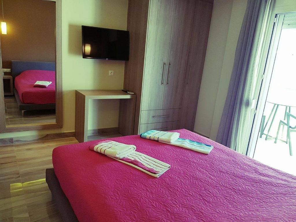 a bedroom with a pink bed with two towels on it at Luxury Apartments Near to the beach in Plakias