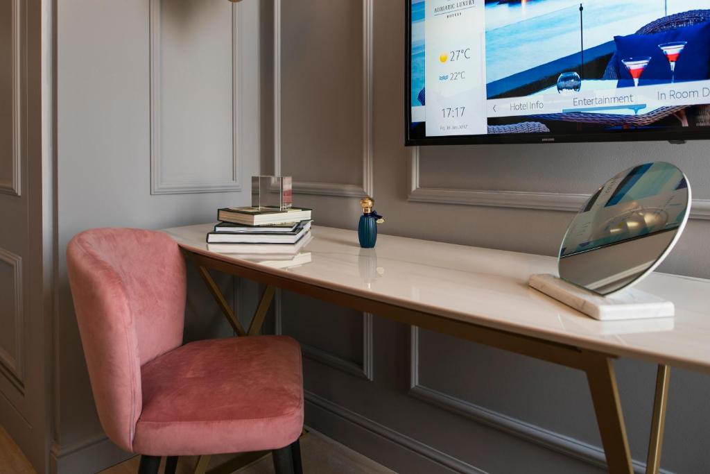 a desk with a chair and a tv on a wall at Hotel Excelsior in Dubrovnik