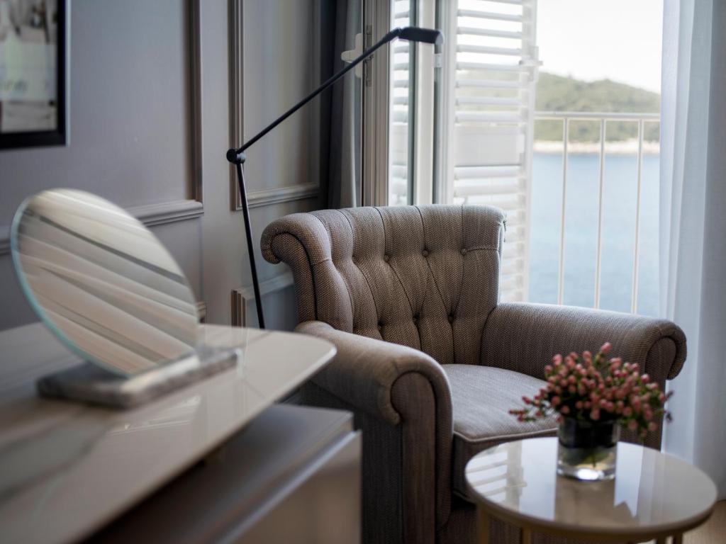 a room with a chair and a table with a mirror at Hotel Excelsior in Dubrovnik