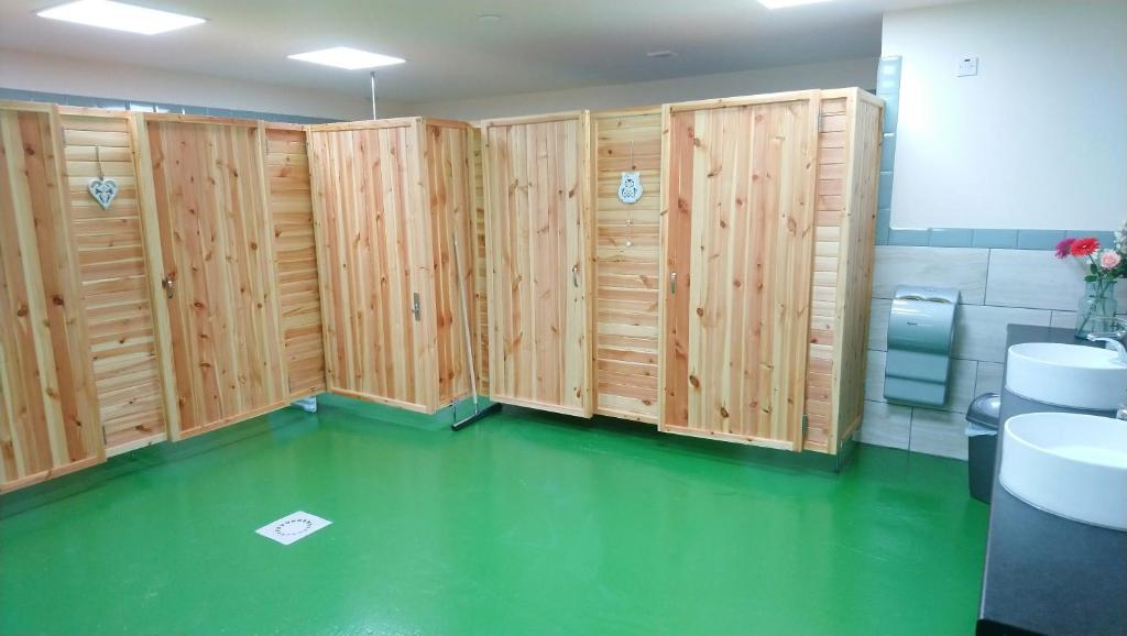 a bathroom with wooden walls and a green floor at Camping Pod Heaven in Brackla