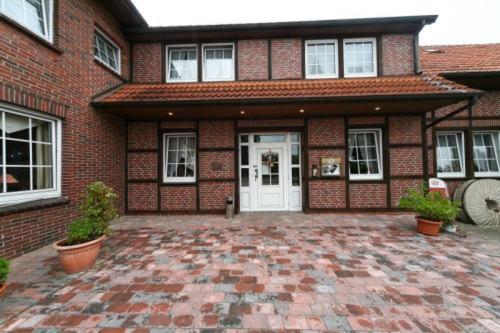 a brick house with a white door and a brick patio at Gasthof zur Mühle in Kirchhatten