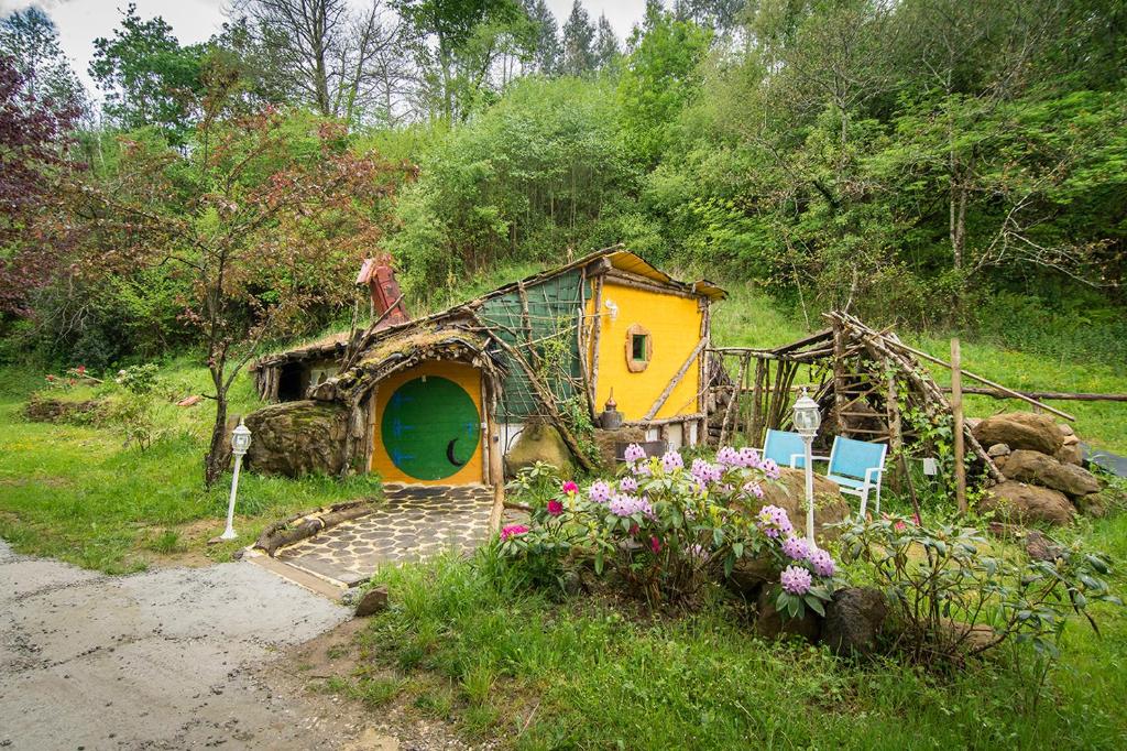 una casa de juegos en un jardín con flores delante en Cabañas Rurales El Hayal, en Aloños