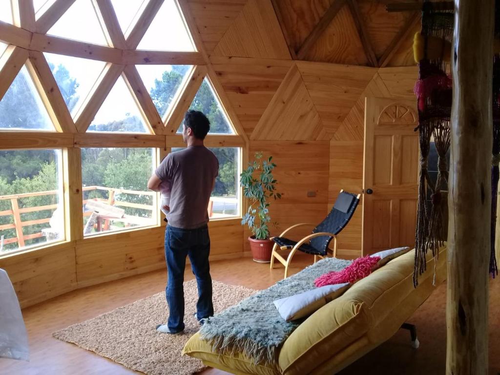 a man standing in a room with a bed at domoschiloe in Ancud