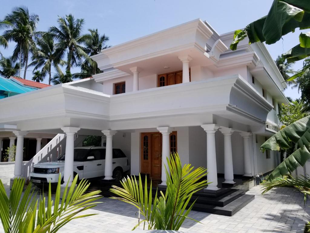 a white house with a white van parked in front at Luxury Villas of Guruvayur in Guruvāyūr