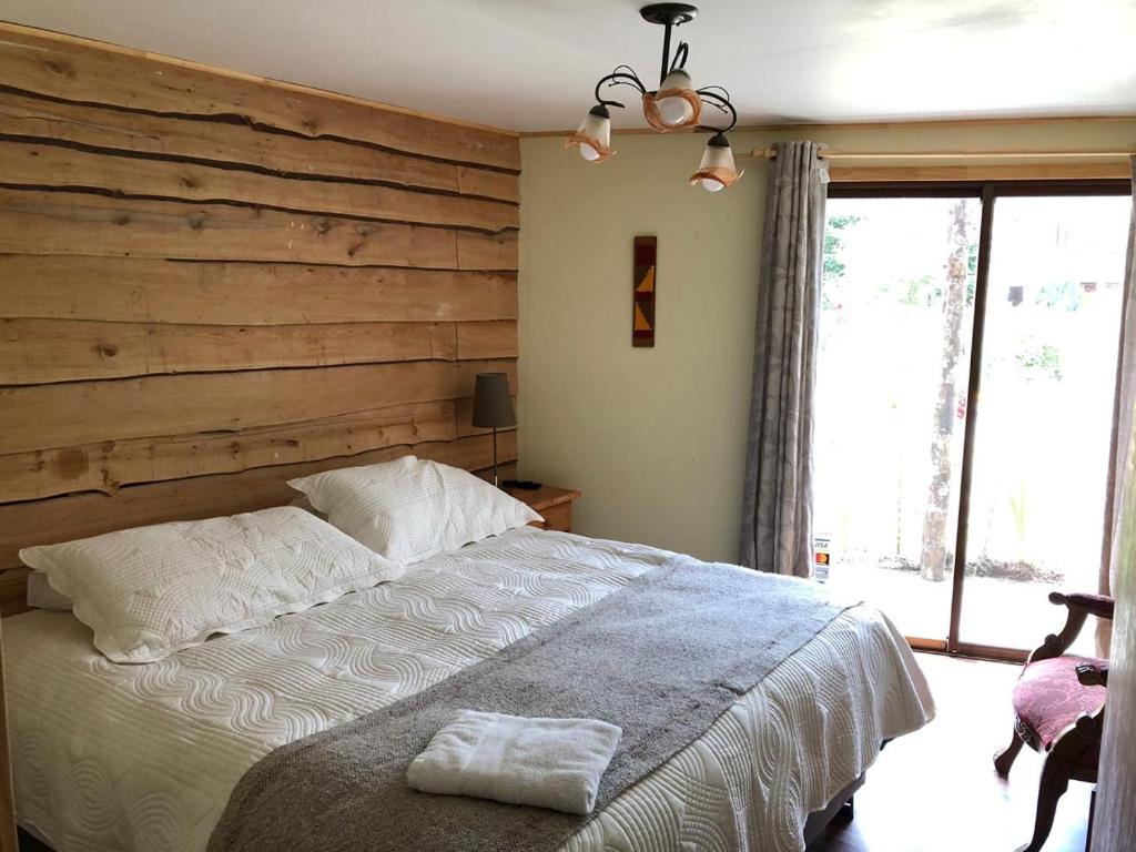 ein Schlafzimmer mit einem großen Bett und einer Holzwand in der Unterkunft Cabanas Senderos Puyuhuapi in Puerto Puyuhuapi