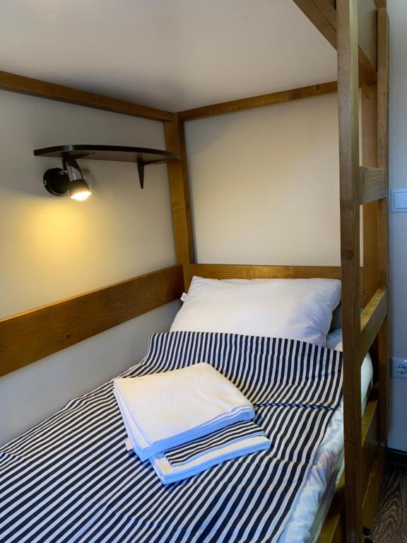 a bed with blue and white striped sheets on it at Hostel Gulliver in Uzhhorod