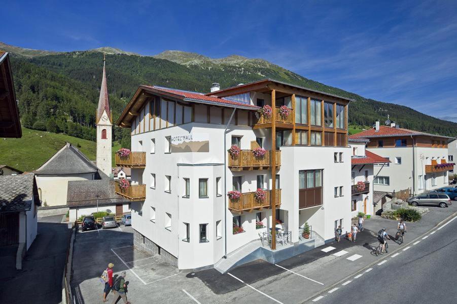 a large white building with balconies and a church at Hotel Mall in San Valentino alla Muta