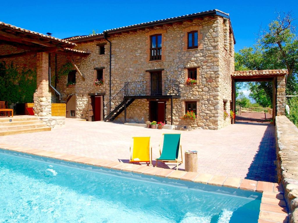 a house with two lawn chairs next to a swimming pool at Cal Pesolet Eco Turisme Rural in Bellver de Cerdanya