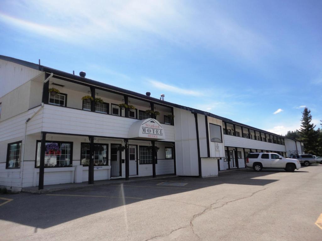 a white building with a car parked in front of it at Stratford Motel in Whitehorse