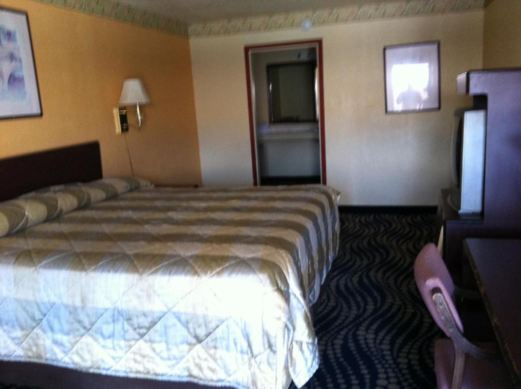 Habitación de hotel con cama y TV en Deluxe Inn Kilgore, en Kilgore