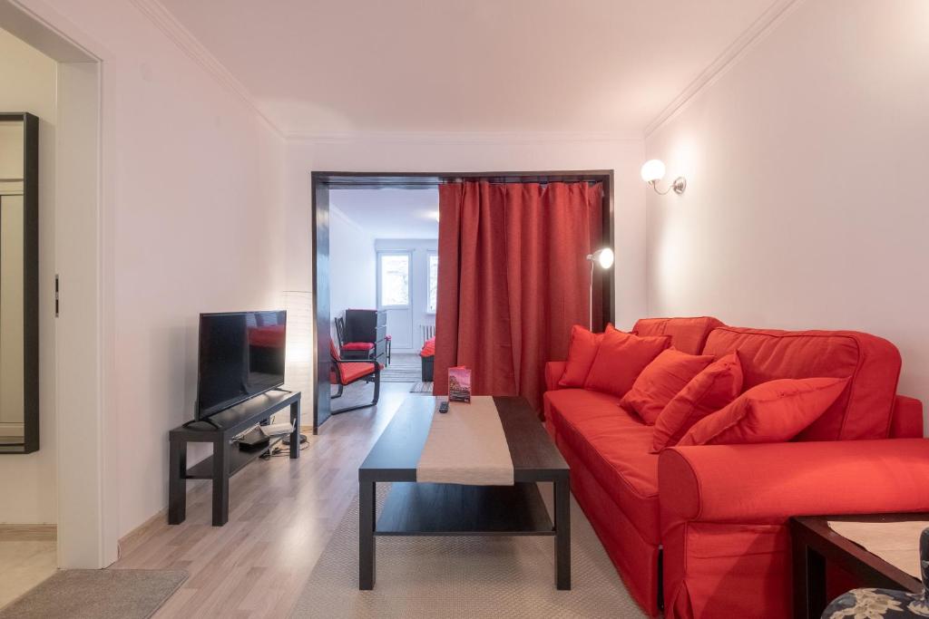 a living room with a red couch and a television at LZ Spacious One Bedroom Apartment in Top Centre in Sofia