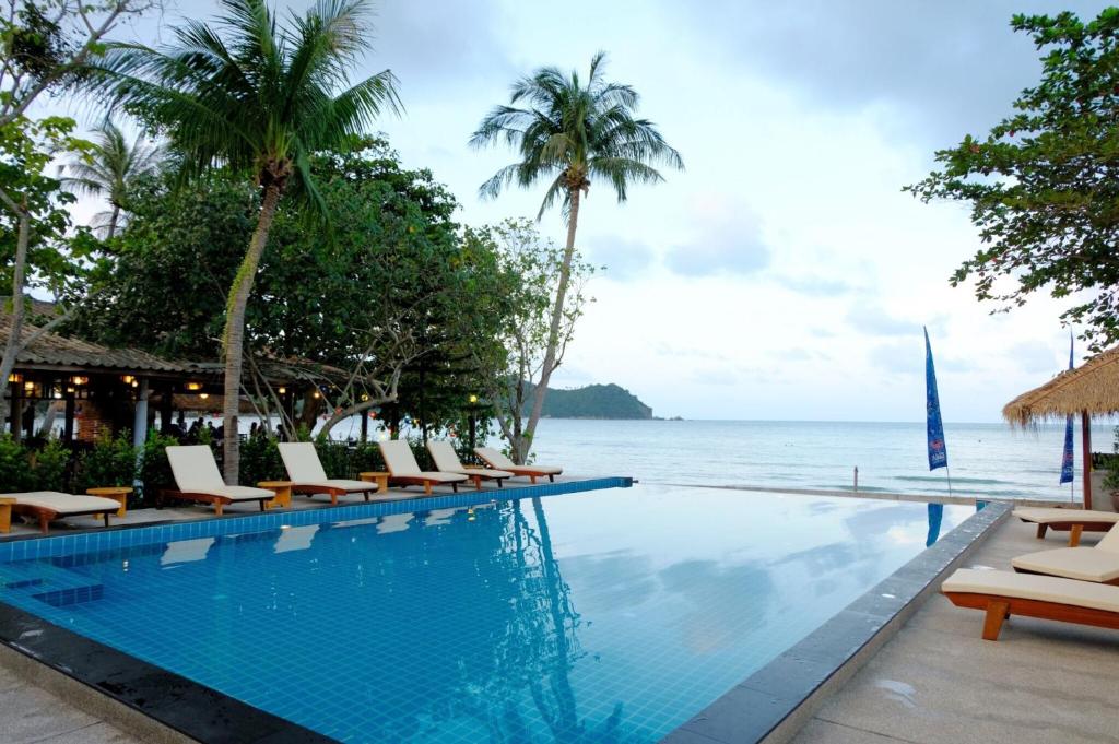 a swimming pool with chairs and a view of the ocean at Pen's Bungalow Koh Phangan in Thong Nai Pan Yai