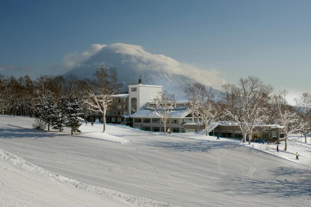 a building in the snow with a mountain in the background at The Green Leaf, Niseko Village in Niseko