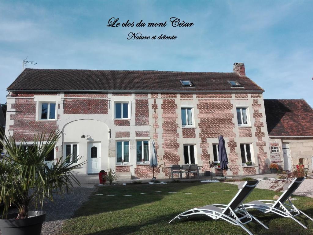 une maison avec deux chaises de jardin devant elle dans l'établissement Le clos du mont César, à Bailleul-sur-ThÃ©rain