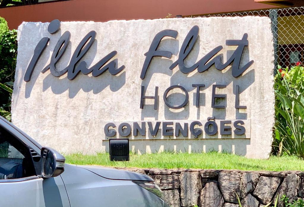 una señal para un hotel con un coche aparcado delante en Flat IlhaFlat Ilhabela, en Ilhabela