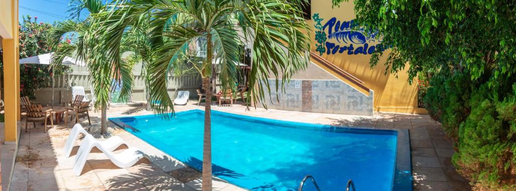 a swimming pool with a palm tree next to a building at Pousada Fortaleza in Canoa Quebrada