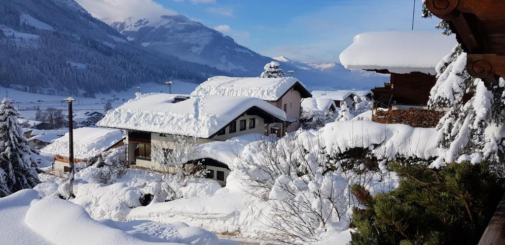 ein schneebedecktes Haus mit Bergen im Hintergrund in der Unterkunft Villa Kitzbühel in Kirchberg in Tirol