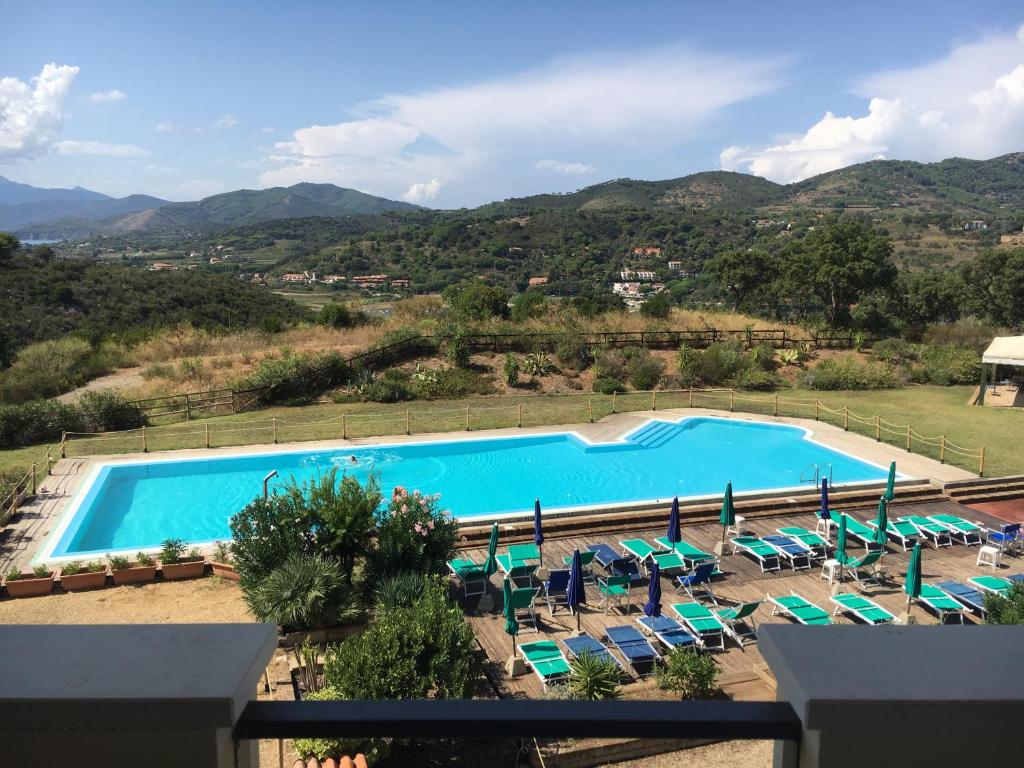 an image of a swimming pool with chairs and umbrellas at Appartamenti Stellamarina in Capoliveri