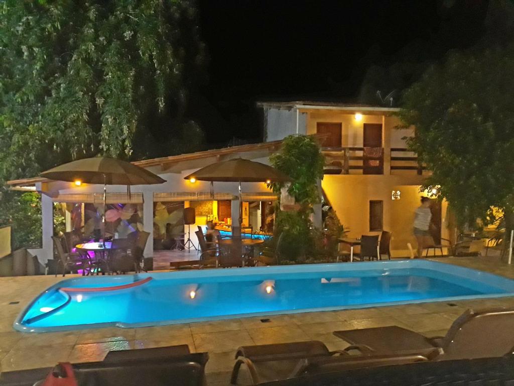 a swimming pool in front of a house at night at Abaquar Hostel in Ilha de Boipeba