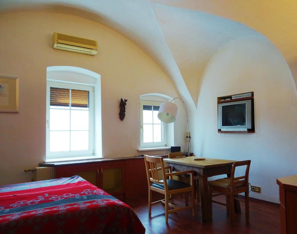 a bedroom with a table and a tv and a bed at Gewölbezimmer am Marktplatz in Gmunden