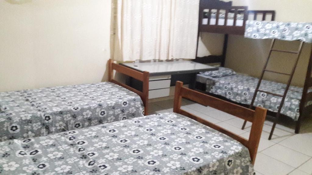 a room with two beds and a table and a chair at Hostel Famille Brun Trevo in São João da Boa Vista