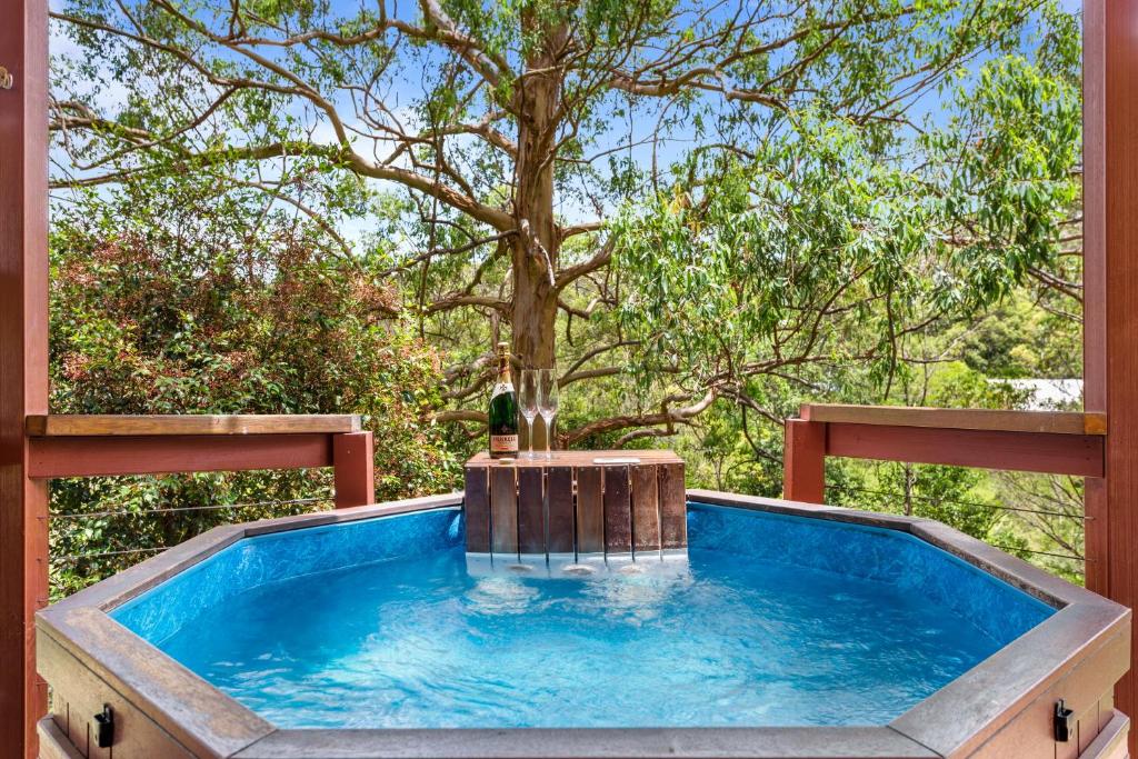 a hot tub on a deck with a tree at Ravensbourne Escape-Tree Tops in Ravensbourne