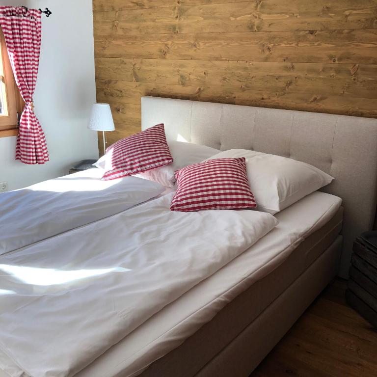 a bed with two red and white pillows on it at Chalet Tirolia in Kirchdorf in Tirol