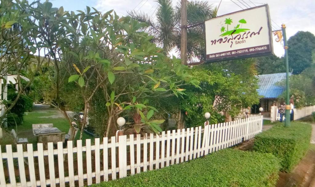 ein weißer Gartenzaun mit einem Schild für ein Restaurant in der Unterkunft Thongsuwan Resort in Chao Lao Beach