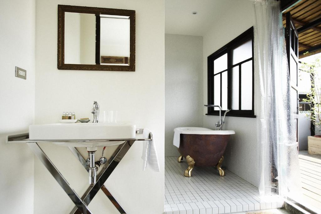 a bathroom with a tub and a sink and a mirror at Hour Roots in Tainan