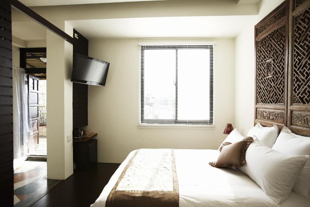a bedroom with a bed with a television and a window at Hour Roots in Tainan