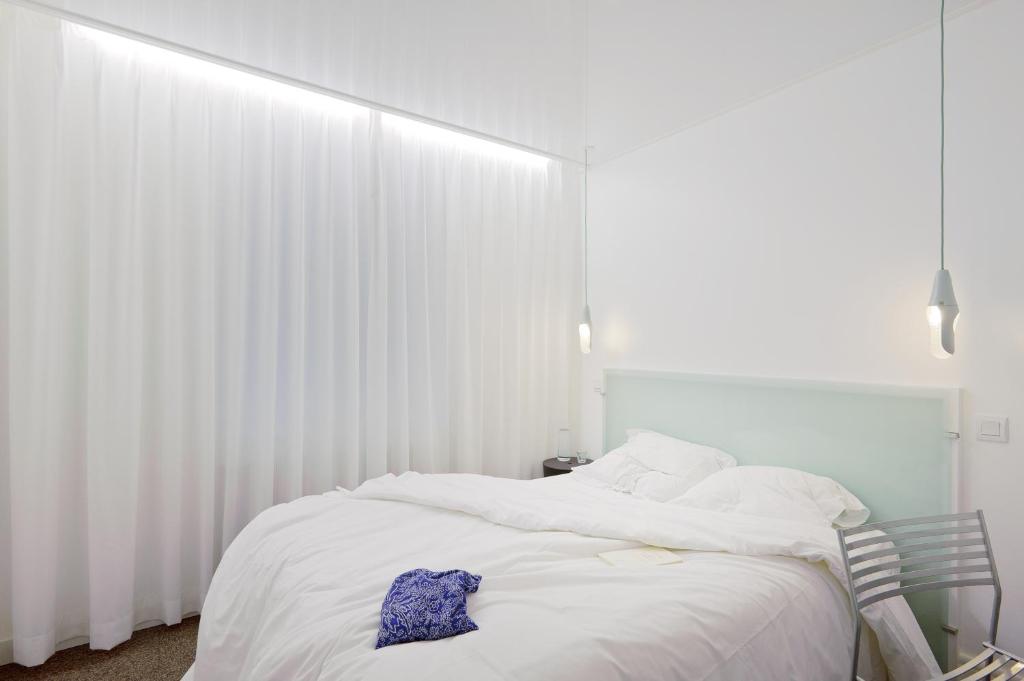 Schlafzimmer mit einem Bett mit weißen Vorhängen in der Unterkunft HOTEL CONTINENTAL in Saint-Étienne