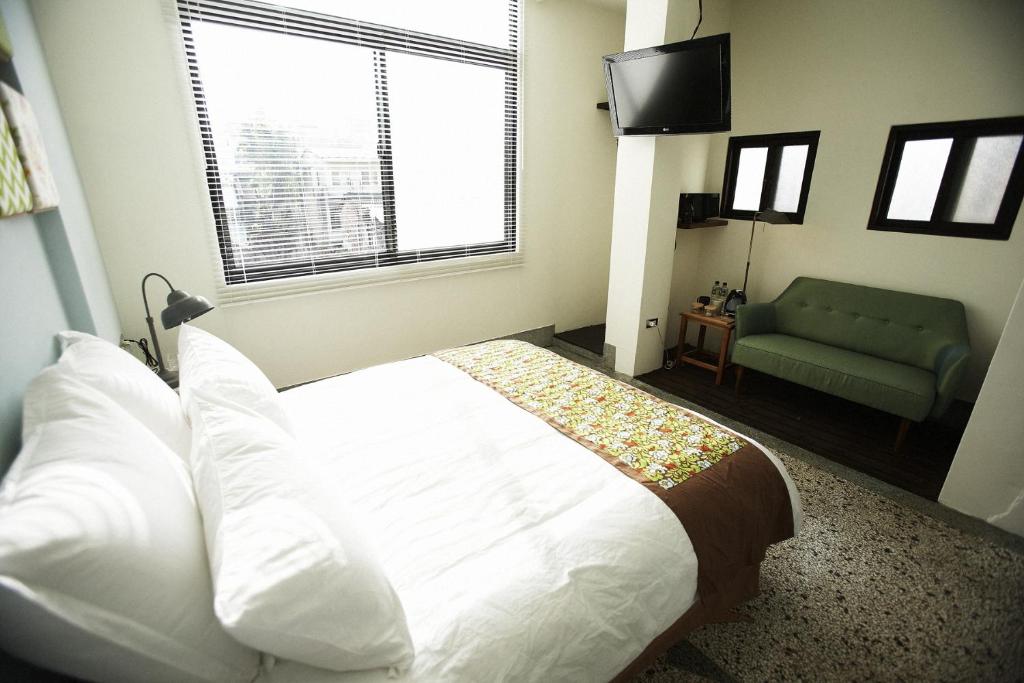 a bedroom with a white bed and a green couch at Hour Roots in Tainan