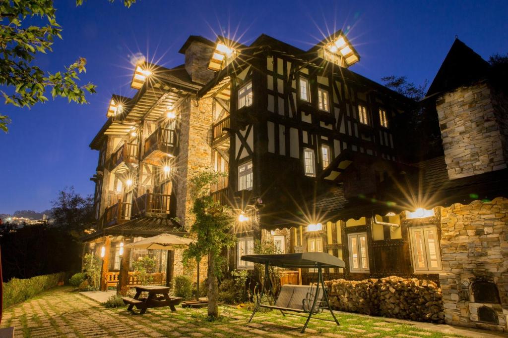 un grand bâtiment avec des lumières allumées la nuit dans l'établissement Black Forest Manor, à Renai