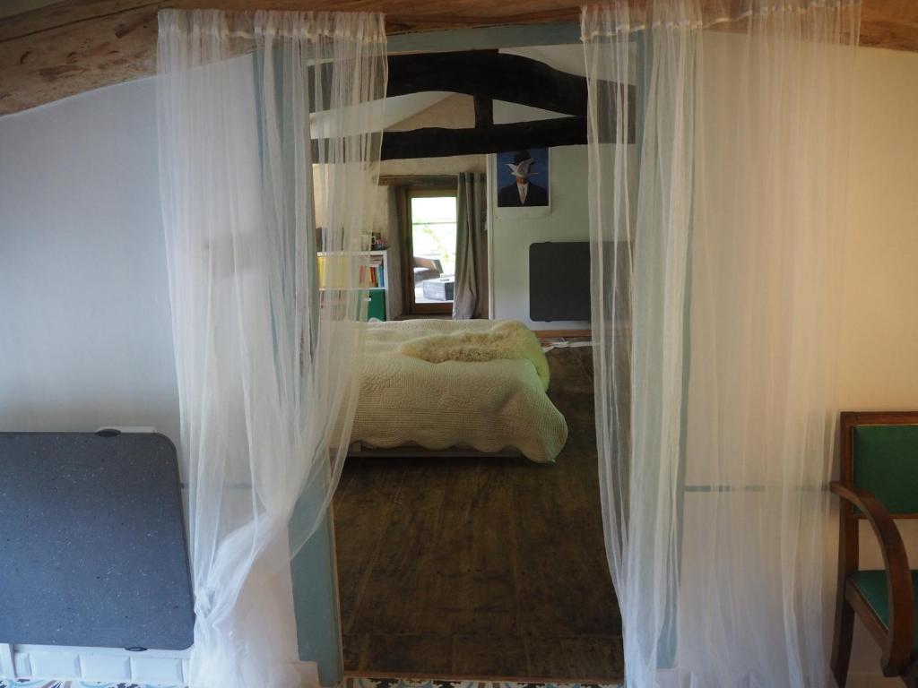 Valsonne的住宿－Le Chatel en Beaujolais，一间设有白色窗帘的卧室和一张位于客房内的床
