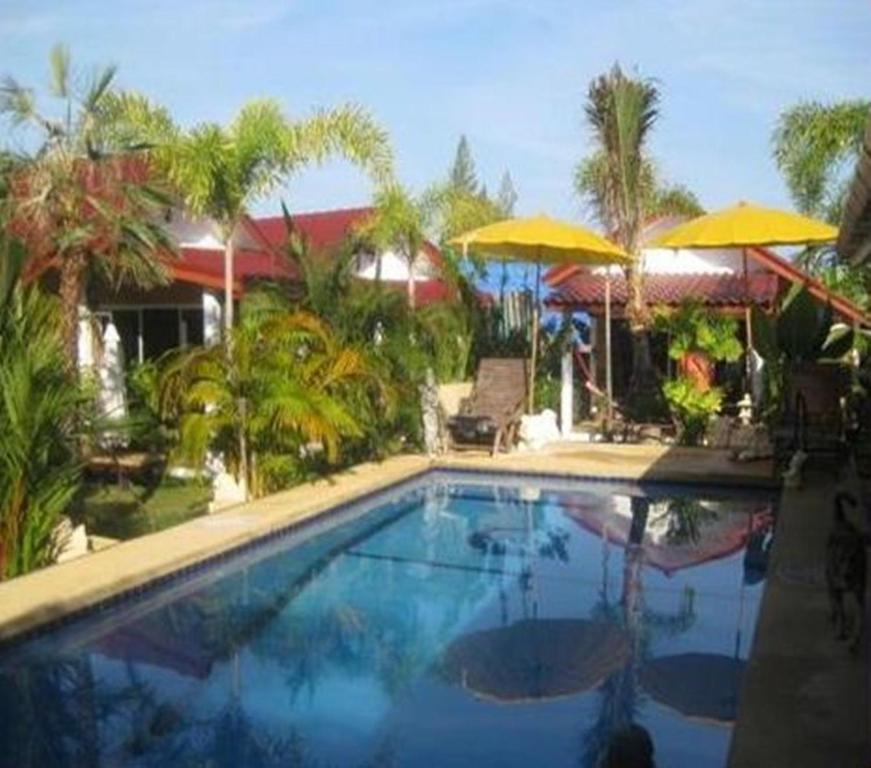 una piscina con sombrillas y una casa en Sanuk bungalows, en Rawai Beach