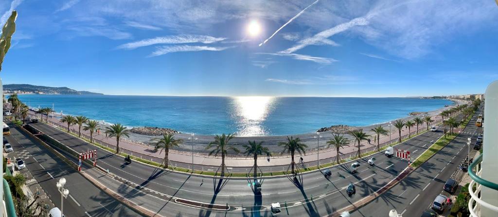 Blick auf eine Straße und das Meer mit Palmen in der Unterkunft Florida Blue - Easy Home Booking in Nizza