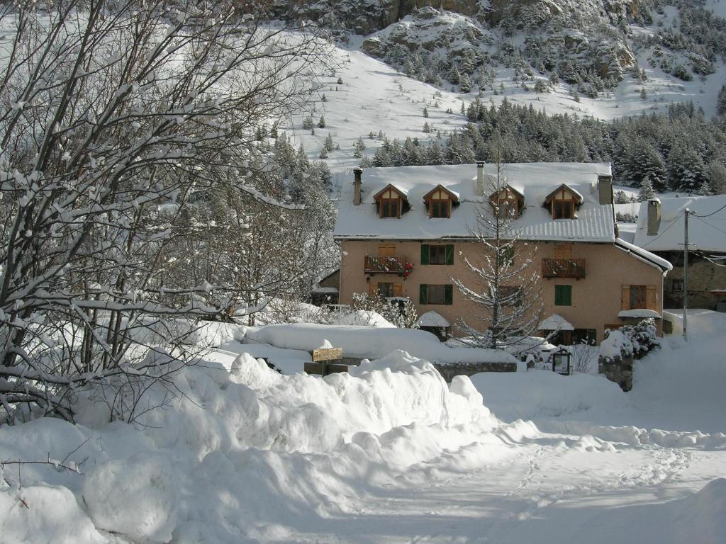 a house covered in snow with a pile of snow at Auberge La Cleida in Névache