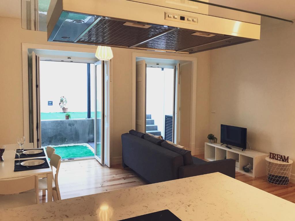 een woonkamer met een bank, een tafel en een televisie bij Senhora do Monte Apartment 2(esq) with Outdoor Space in Lissabon