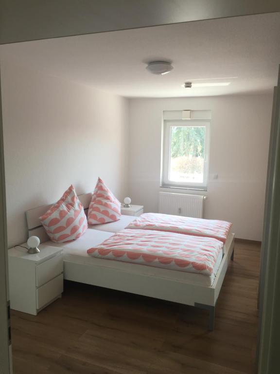 ein Schlafzimmer mit einem Bett mit zwei Kissen und einem Fenster in der Unterkunft Mara in Bad Nauheim
