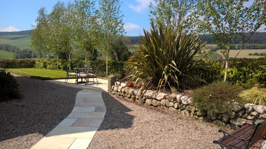 un giardino con panchina e muro di pietra di Macreddin Rock Bed & Breakfast a Aughrim