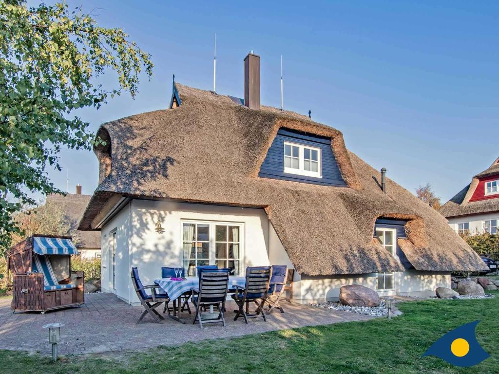 a thatched house with a table and chairs in front at Haus Klabautermann in Heringsdorf