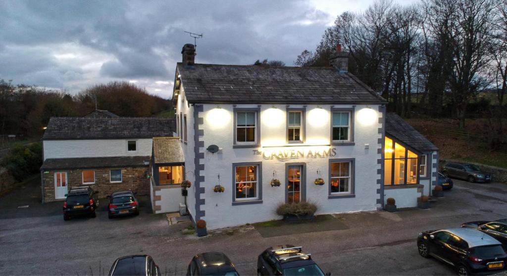 un edificio blanco con coches estacionados en un estacionamiento en The Craven Arms en Settle